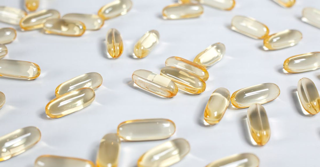 A flatlay of everyday vitamin and supplement bottles with capsules scattered on a white surface, representing the best everyday vitamins & supplements 2026.