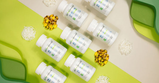 A lineup of amber glass bottles of best b-complex for energy supplements on a light wooden surface, with fresh green leaves for a natural vitality feel.