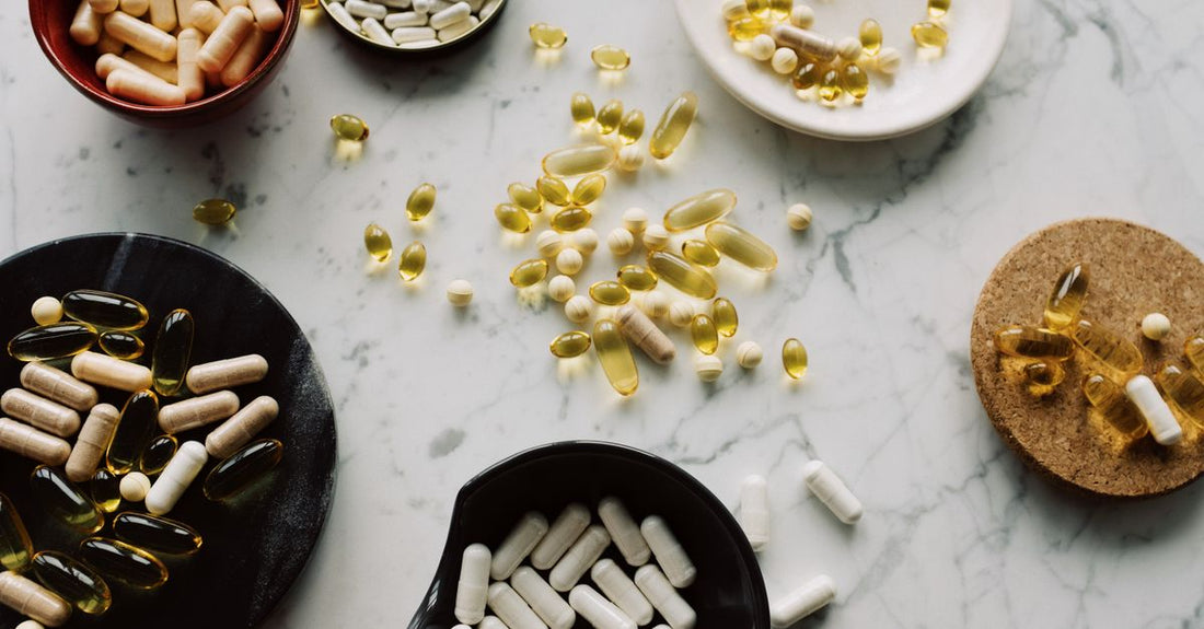 A flatlay of everyday vitamins and supplements including multivitamins, fish oil, and vitamin D on a light background, representing the best everyday vitamins & supplements 2026.
