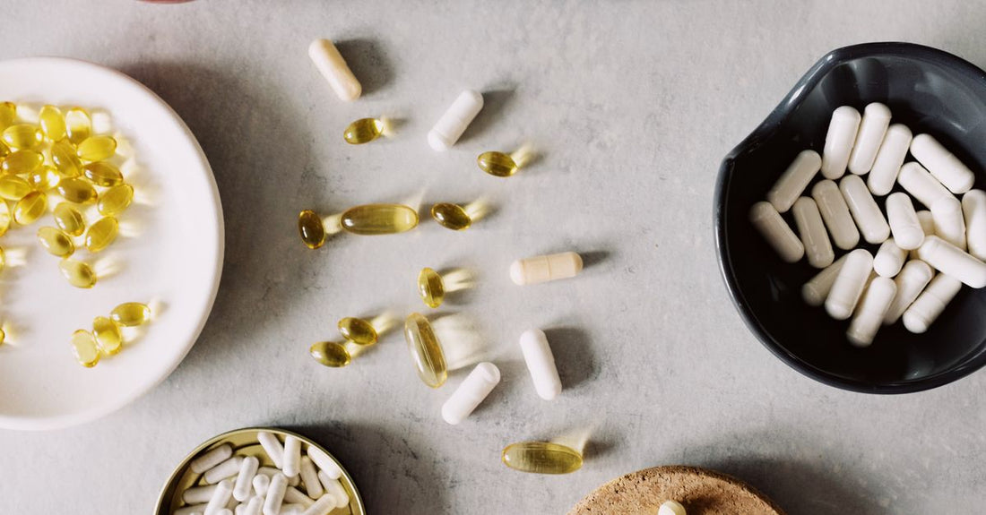 An assortment of colourful vitamin and supplement bottles arranged on a light surface, representing the best everyday vitamins & supplements 2026 for gifting.