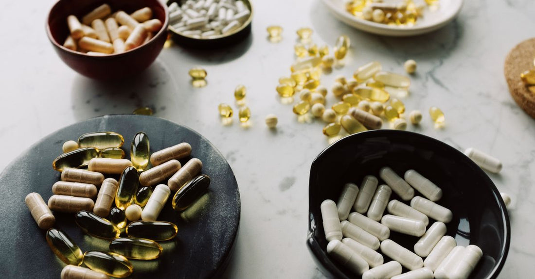 A flatlay of everyday vitamins and supplement bottles on a clean white surface, illustrating how to choose everyday vitamins & supplements.