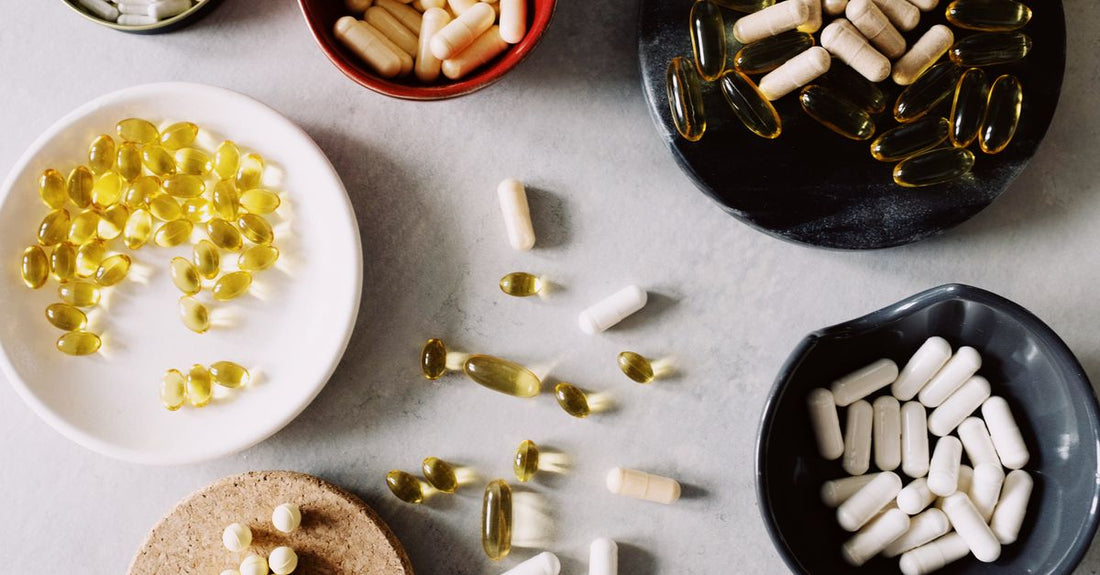 A flatlay arrangement of everyday vitamins and supplement bottles on a light surface, illustrating how to choose everyday vitamins & supplements.