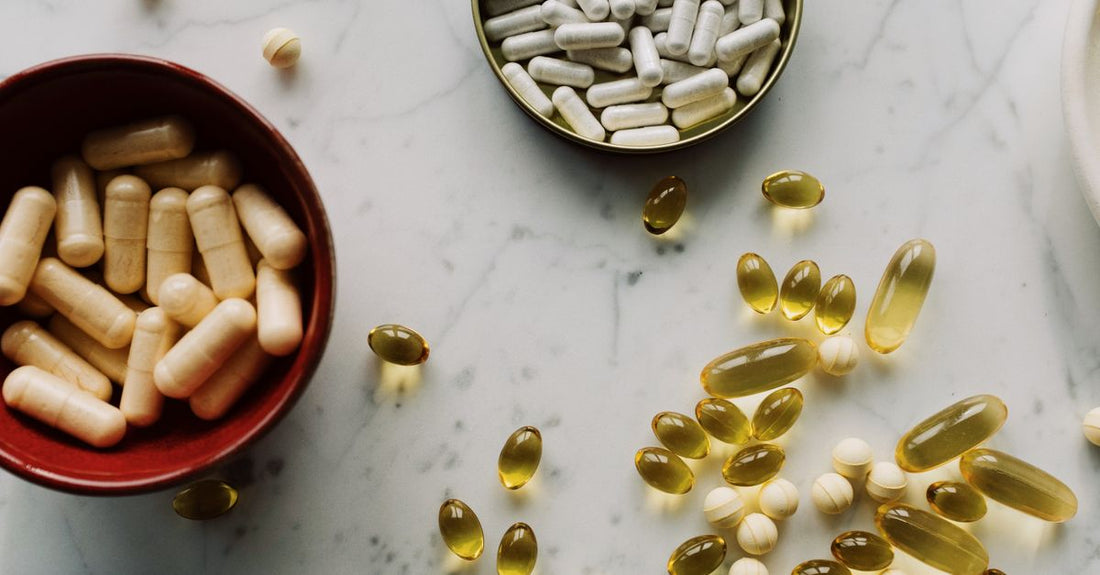 An assortment of everyday vitamins and supplements bottles and capsules on a clean surface, illustrating how to choose everyday vitamins & supplements.
