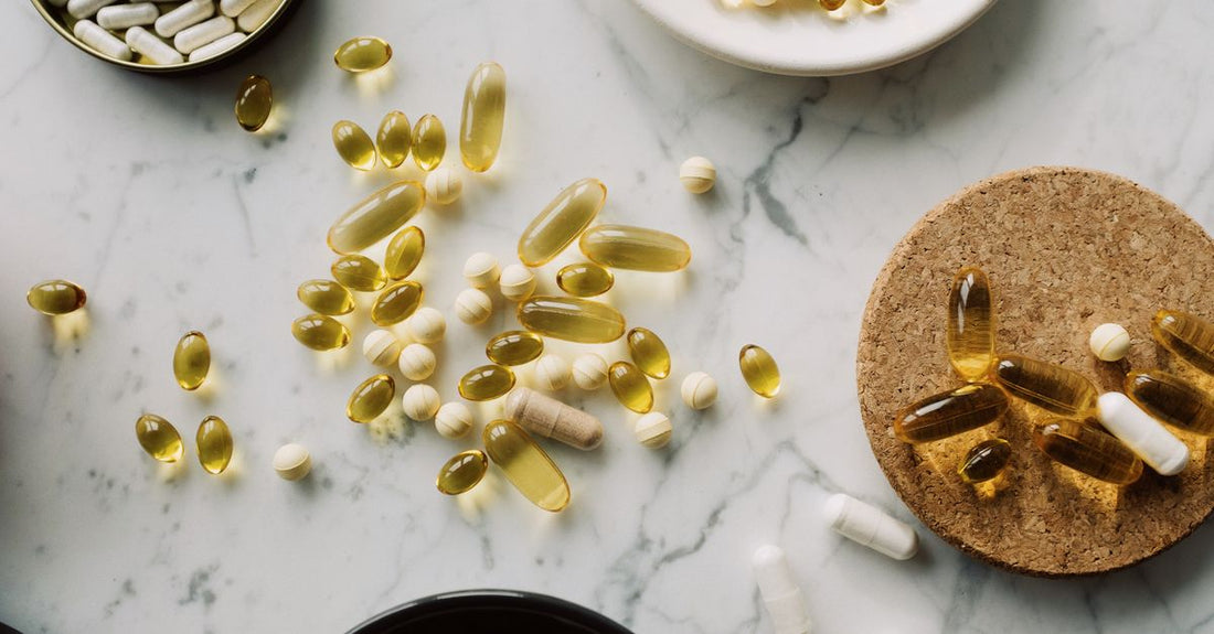 A flatlay of everyday vitamin and supplement bottles on a white surface, representing how to choose everyday vitamins & supplements.