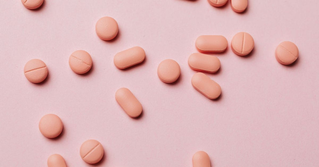 A flat lay of colourful everyday vitamin and supplement bottles and capsules on a light background, illustrating how to choose everyday vitamins & supplements