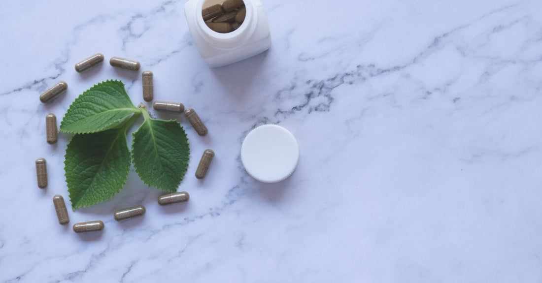 Flatlay of everyday vitamins and supplements bottles on a light marble surface, showing a buying guide comparison.