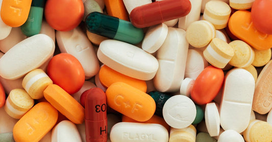 Assorted multivitamin tablets and capsules spilling from a glass bottle, representing a daily multivitamin for women over 50 in Australia.
