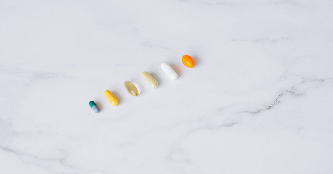 A flatlay of best everyday vitamins & supplements 2026 bottles on a light background, featuring multivitamin, omega-3, vitamin D, magnesium, and probiotic containers.