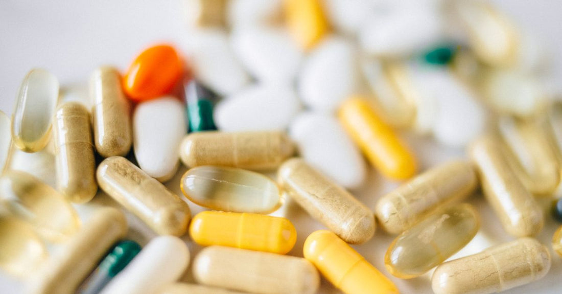 A flatlay of everyday vitamins and supplements including multivitamins, fish oil, and probiotics on a light background, representing the everyday vitamins & supplements buying guide.