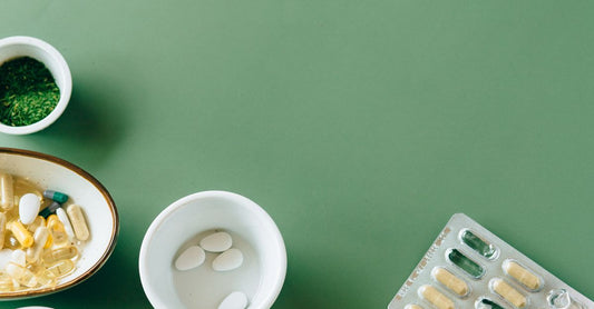 A flat lay of vitamin B9 supplements including folic acid and methylfolate capsules on a white background, illustrating the folic acid vs folate debate.
