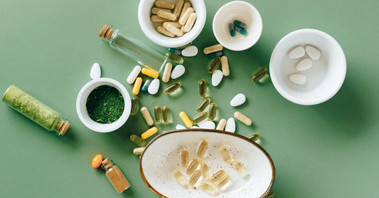 A flatlay photograph of vitamin C supplements including capsules, tablets and powder on a clean white surface, representing how much vitamin C per day you might take.