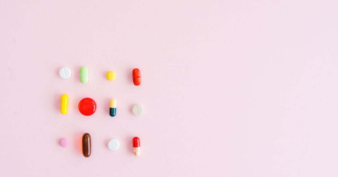 A flatlay of everyday vitamins and supplements including fish oil, multivitamin, magnesium, and probiotic capsules on a light background, illustrating how to choose everyday vitamins & supplements.